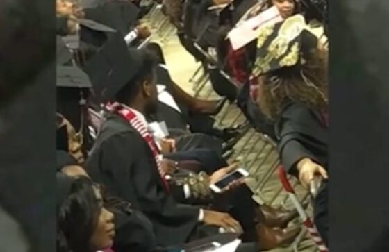 A group of people are sitting in a row at a graduation ceremony, surprised by student's large pet python.
