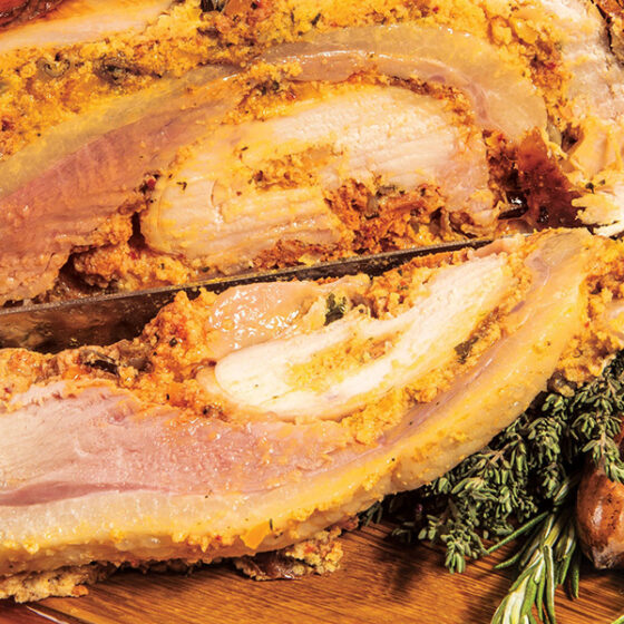 A manly ham adorned with rosemary and thyme displayed on a rustic wooden board.