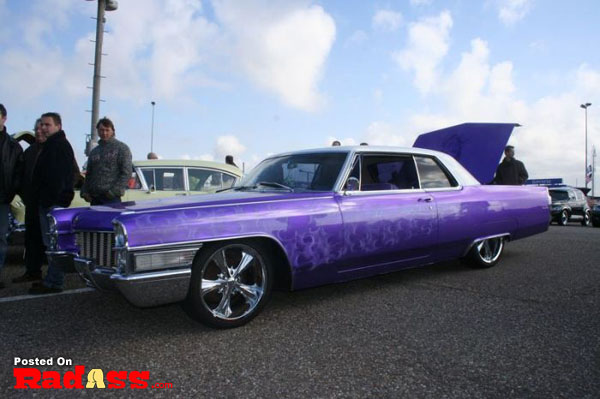 A purple cadillac parked in a parking lot, unnoticed.