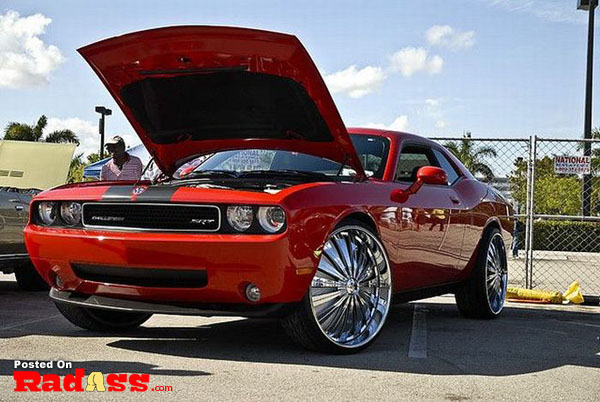 A red dodge challenger with its hood open draws attention.
