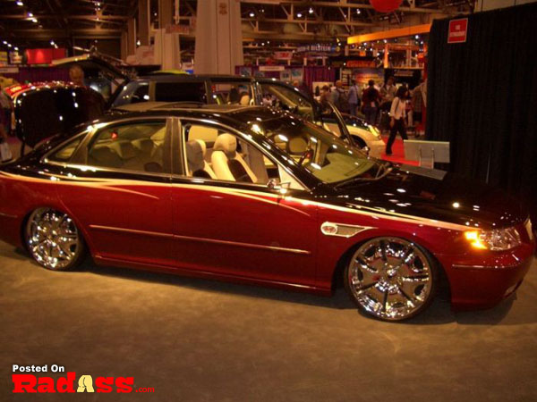 A chrome-rimmed red car steals attention at a show.