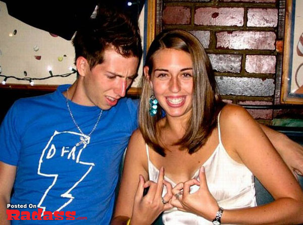 A man and woman posing for a picture in a bar, exploring the widespread popularity of boobs.
