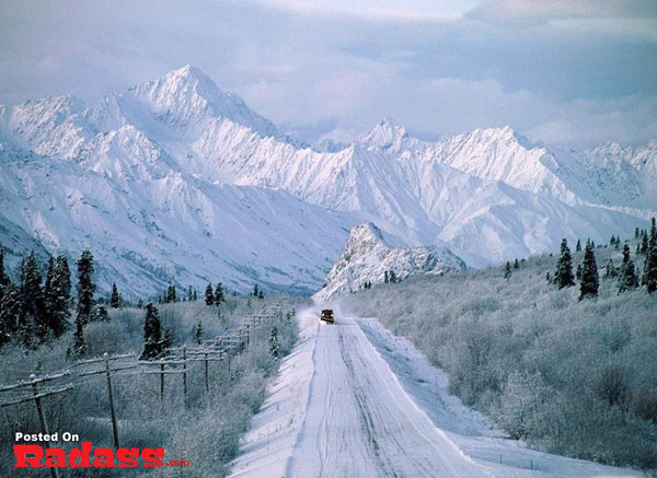 A snow covered road with mountains in the background. (Keywords: snow, mountains)