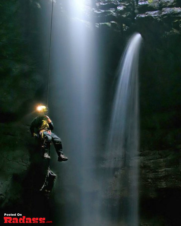 A man hangs in front of a waterfall, immersed in tranquility.