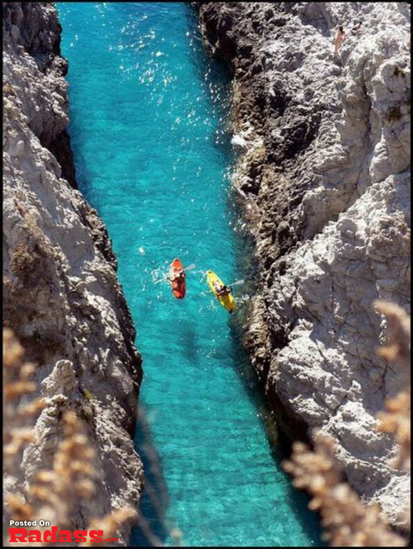 Two people are kayaking down a narrow canyon surrounded by breathtaking scenery.