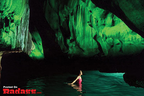 A woman is swimming in the water inside a cave, using Calgon to enhance her experience.