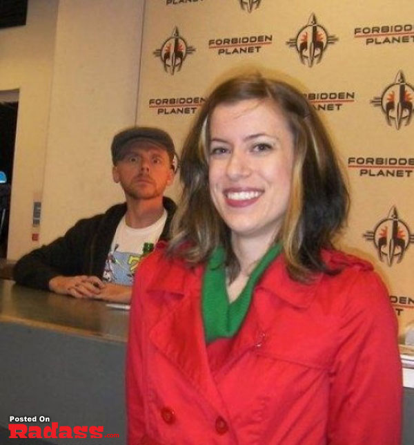 A woman in red photobombs a celebrity at a convention.
