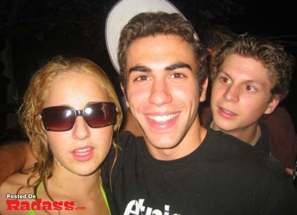 A group of people photobombing a celebrity-style picture at a party.