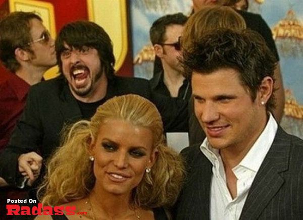 A celebrity photobombs a man and woman posing for a picture on the red carpet.