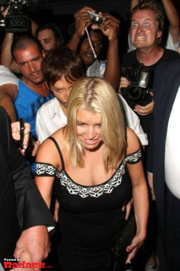 A woman in a black dress photobombs celebrity style as she is surrounded by photographers.