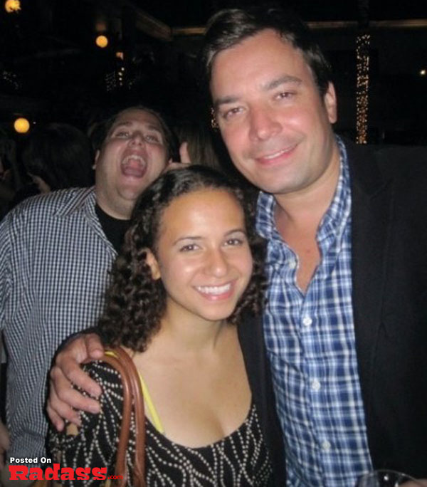 A man photobombs a woman posing for a picture at a party.