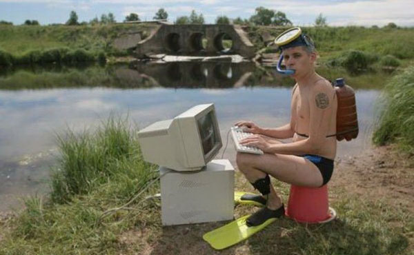 A man in a bathing suit sitting on a computer, giving off WTF vibes.