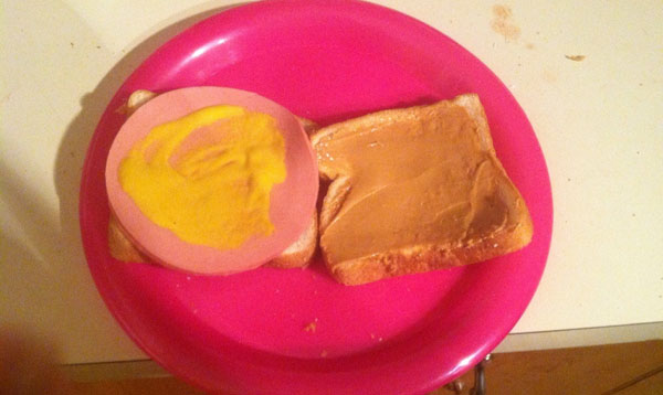 A college essential, the peanut butter and jelly sandwich, presented on a vibrant pink plate.