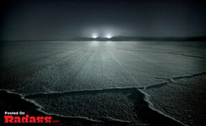 A stunning night-time photo of a frozen lake illuminated by a radiant light.