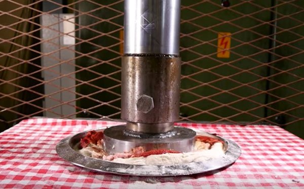 A hydraulic press is used to make a pizza.