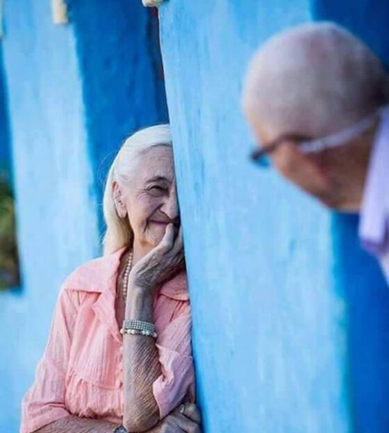 An older couple looking at each other through a blue wall. If a Smile is Worth a Thousand Words, Here’s a Dictionary.