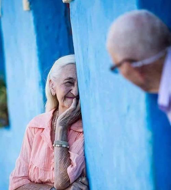 An older couple looking at each other through a blue wall. If a Smile is Worth a Thousand Words, Here’s a Dictionary.