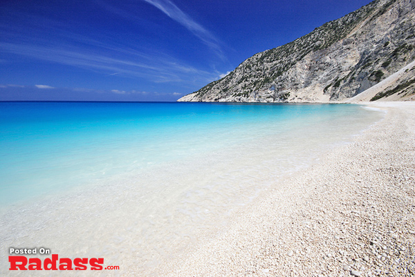 A picturesque beach with crystal-clear water and a vibrant blue sky.