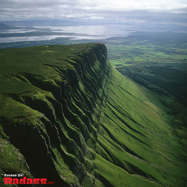 An image of a green cliff with a lake in the background, perfect for your bucket list.