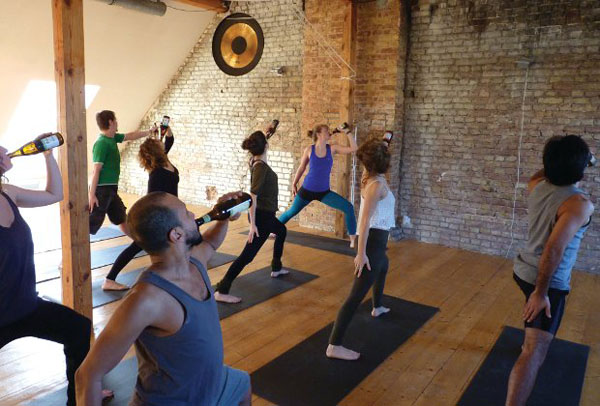 A group of people doing Beer and Yoga in an empty room.
