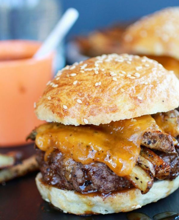 An awesome burger with cheese and fries on a plate.