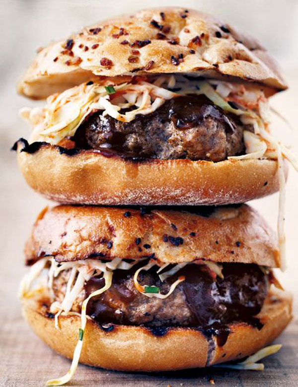 A stack of AWESOME burgers with SLAW and coleslaw.