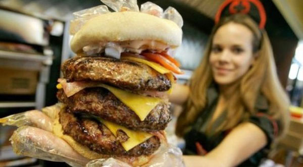 A woman showcases a massive burger filled with innovative ingredients, presenting awesome burger ideas for 2022.