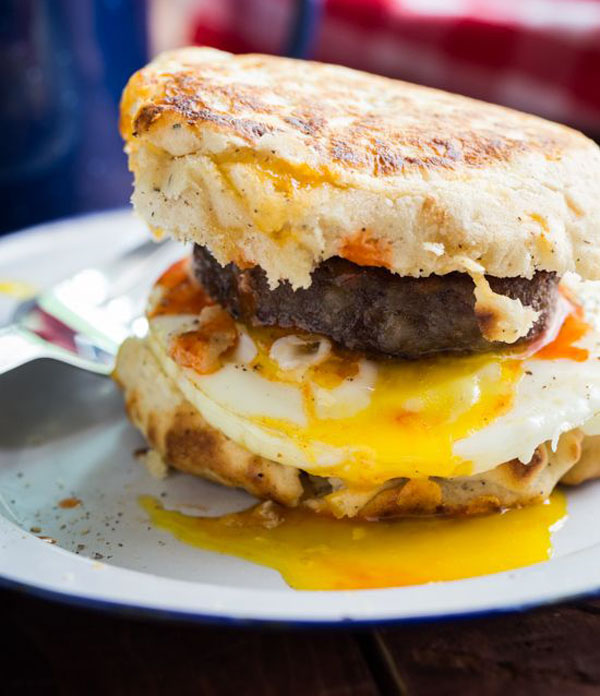 A delicious breakfast sandwich featuring eggs and bacon served on a plate, providing awesome burger ideas for 2022.