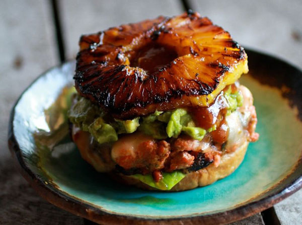 An awesome burger idea for 2022 featuring a pineapple burger with guacamole on a plate.