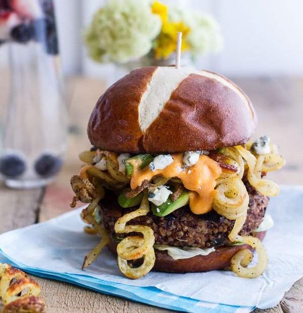 An awesome 2022 burger piled high with onions and cheese, served on a rustic wooden plate.