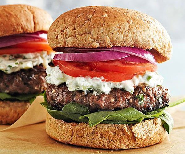 Two delectable burgers showcasing tomatoes and onions, displayed on a rustic wooden board.