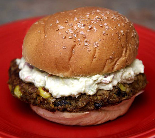 An awesome burger is sitting on a red plate.
