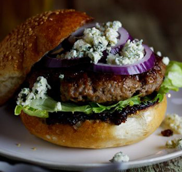 A mouthwatering burger with blue cheese and onions served on a plate.