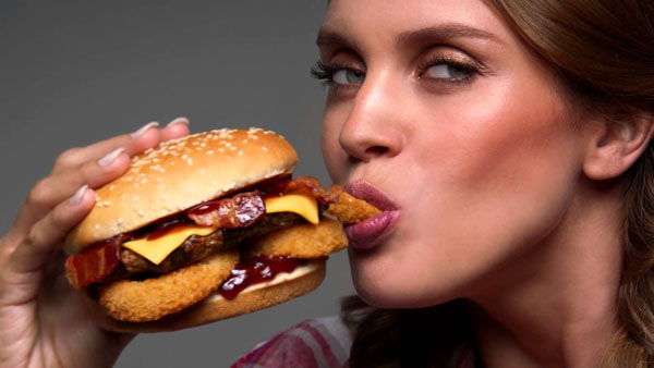 A woman enjoys an awesome burger with bacon and chicken in 2022.