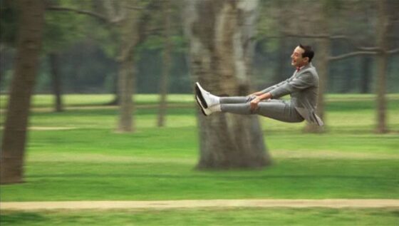 A man in a suit defying physics by jumping in the air with immense style and grace.