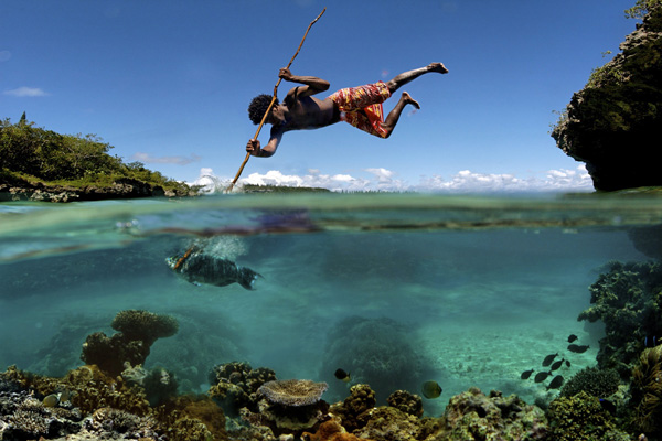 A cool pic of a man swimming with a stick in the ocean.