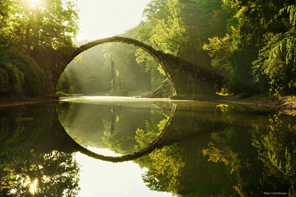 A cool bridge is reflected in a body of water, brightening your day with its serene beauty.