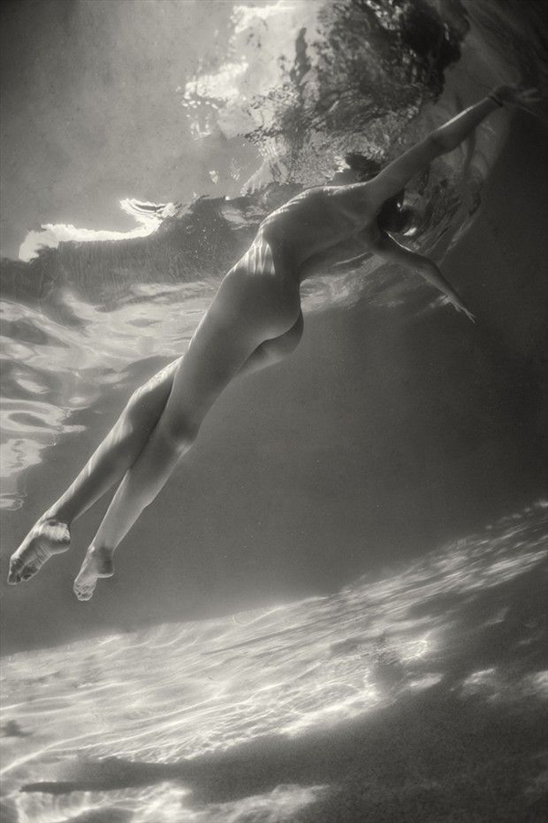A black and white photo of a woman swimming underwater, bringing you plenty of cool pics.