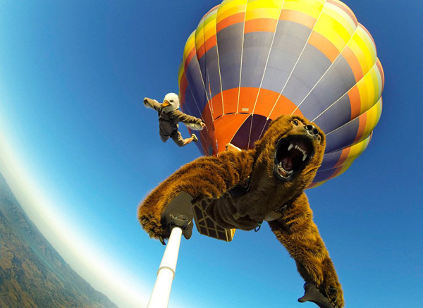 A man is jumping from a hot air balloon with a bear attached to it, creating cool pics to make your day.