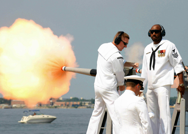 A group of sailors firing a cannon with plenty of cool pics.