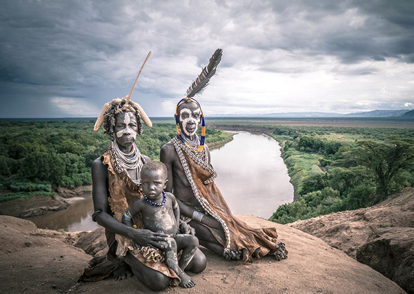 Three Ethiopian tribesmen sit on top of a cliff overlooking a river, providing a cool pic to make your day.