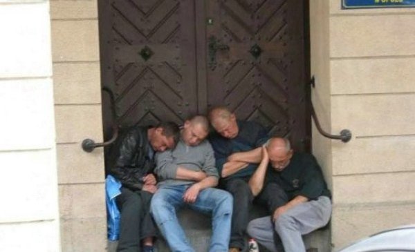 A group of friends sleeping on the steps of a building after drinking excessively.