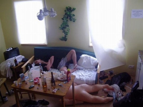 A man is lying on the floor in a disorderly room after excessive drinking with friends.