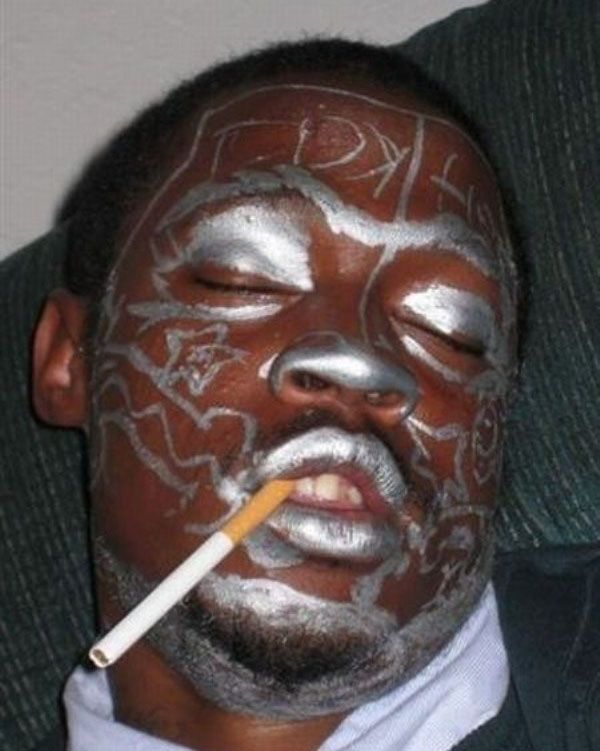 A man smoking a cigarette with silver paint on his face.