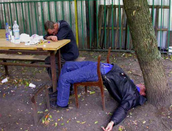 A man is sleeping on a bench after drinking excessively with friends.