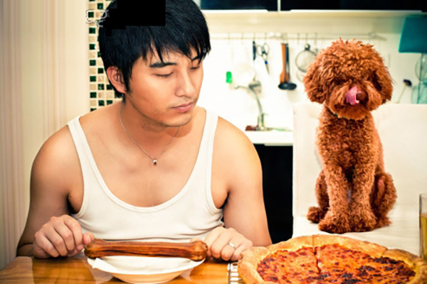 A man enjoying pizza with his furry best friend by his side.