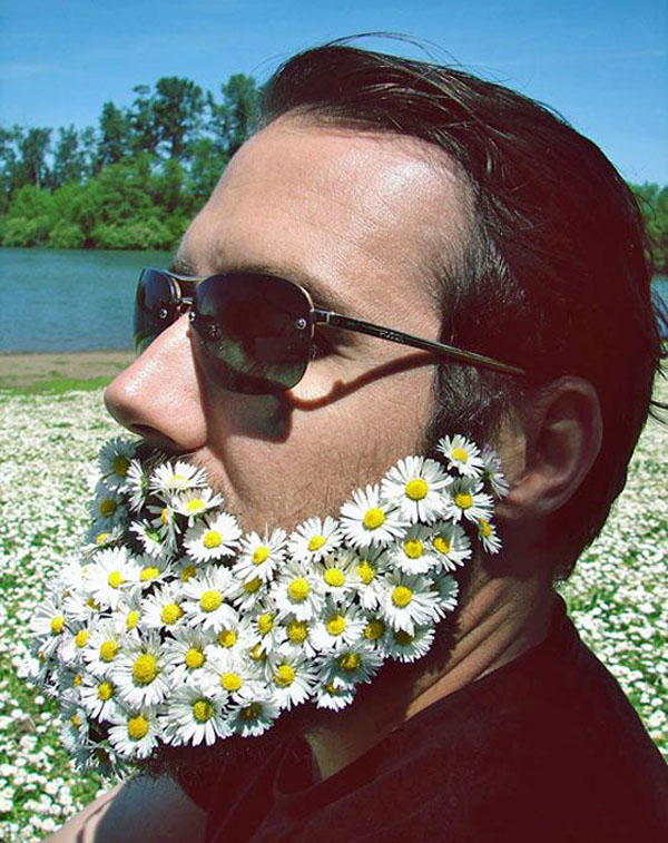 A man with a beard covered in daisies, epitomizing how hipsters have gone too far in their unique and eccentric style choices.