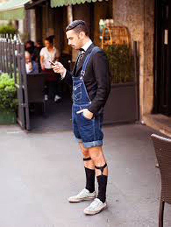 A man wearing denim overalls and a tuxedo, showcasing how hipsters have gone too far in their fashion choices.