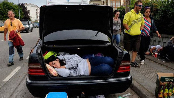 A woman sleeps in the trunk of a car, pondering over 