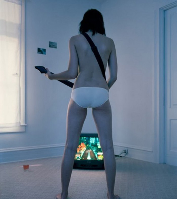 A woman in underwear standing in front of a television, displaying the keywords 